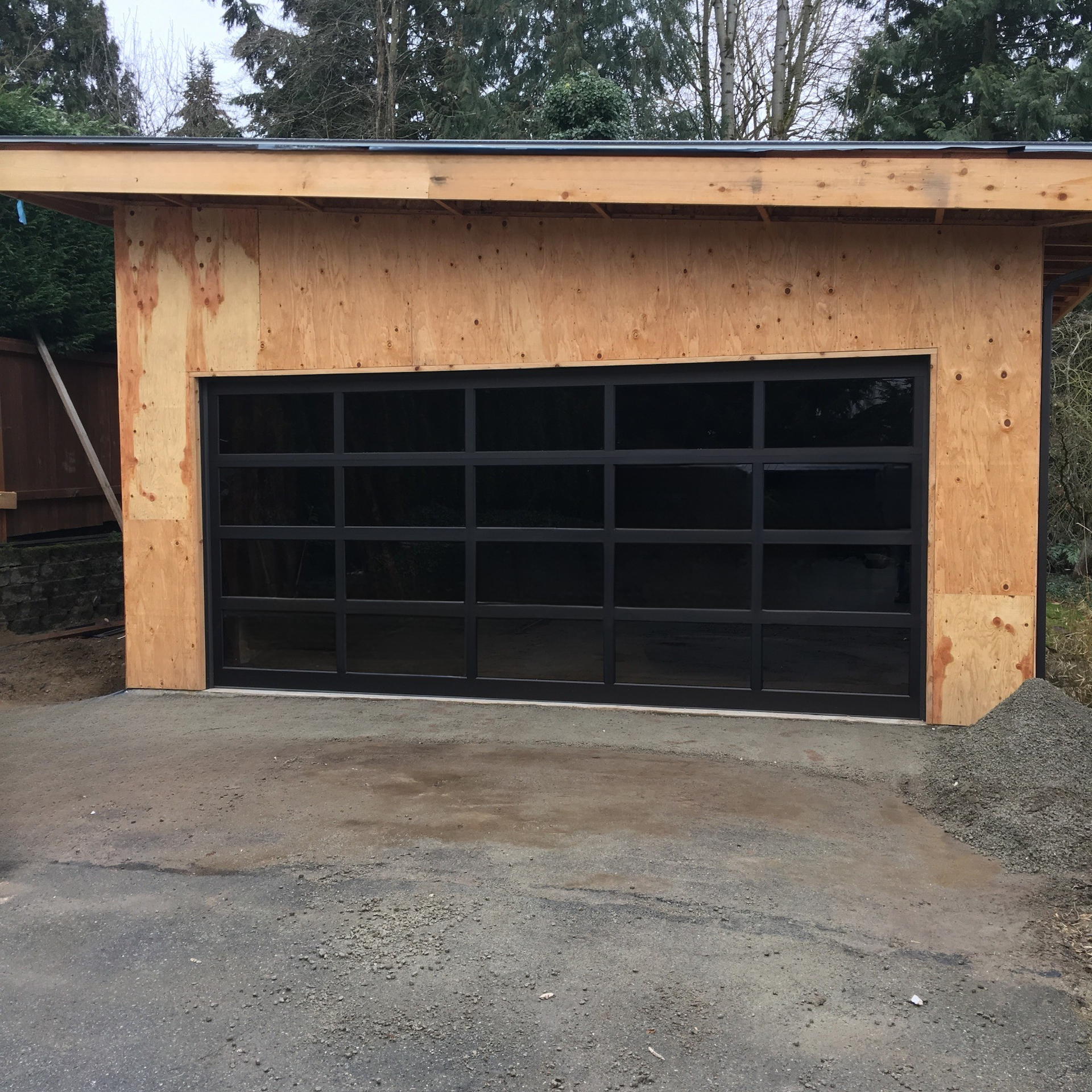 Modern garage door with dark glass panels and black trim installed on an unfinished garage