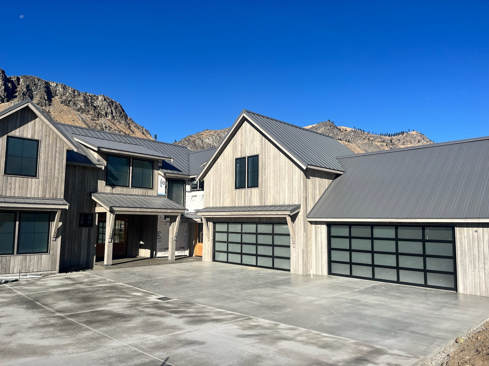 Farmhouse-style home with mountain views and black-frame glass garage doors