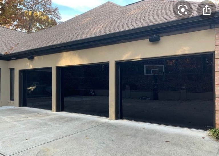 Three-car black-frame glass garage doors on a modern white home