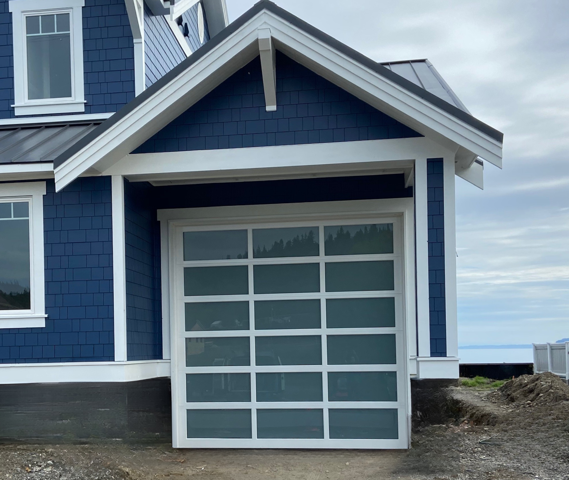 Blue home with a new glass panel contemporary garage door