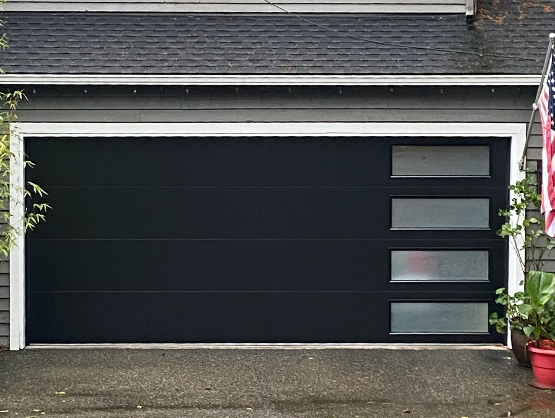 Black contemporary garage door with window accents and American flag