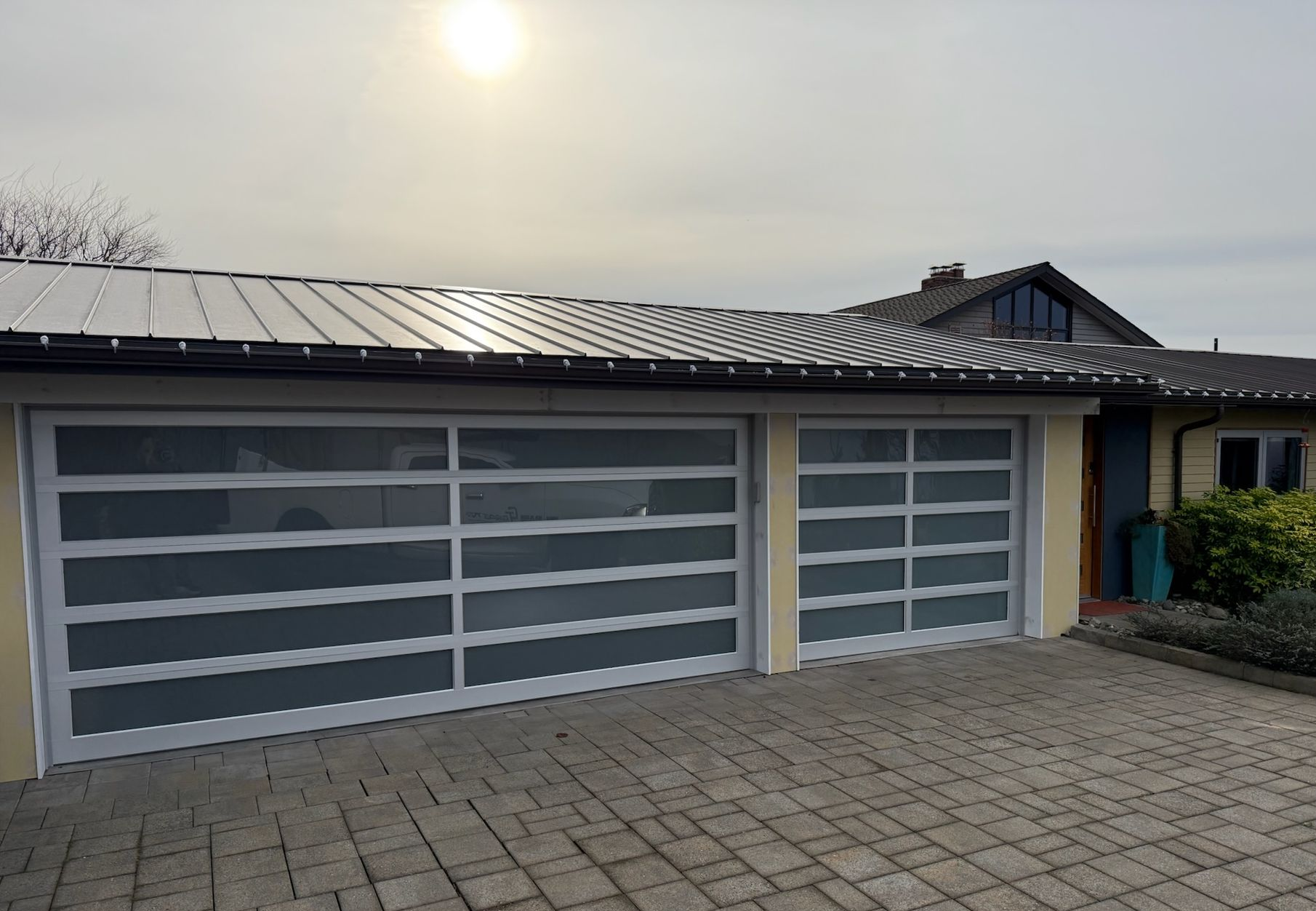 Glass contemporary garage door with paver driveway
