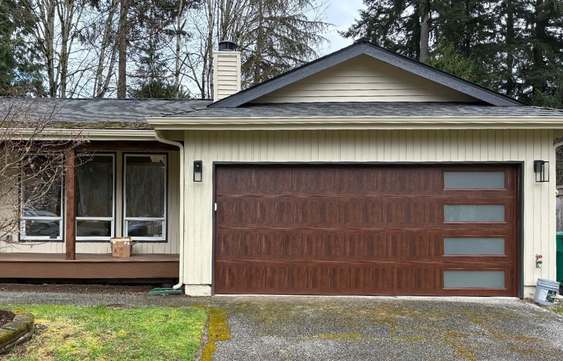 Wood-tone contemporary garage door with window accents on a ranch home