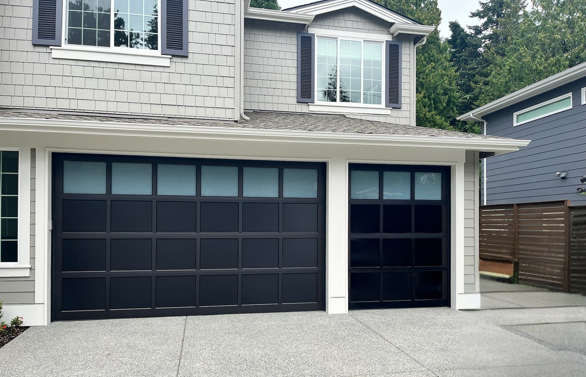 Black-frame full-view glass garage doors on a two-tone home