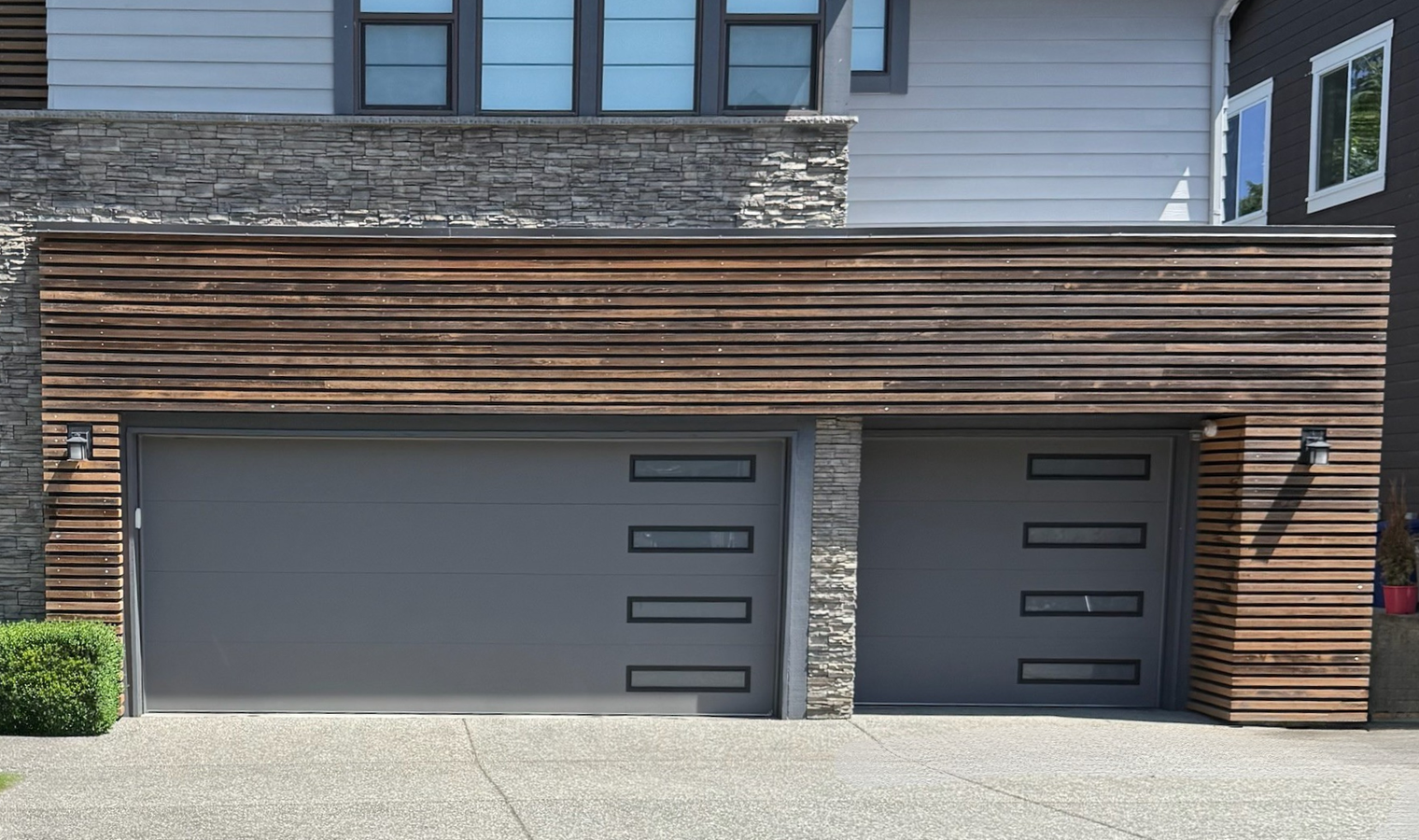 Dark gray contemporary garage door on a wood-slat modern home