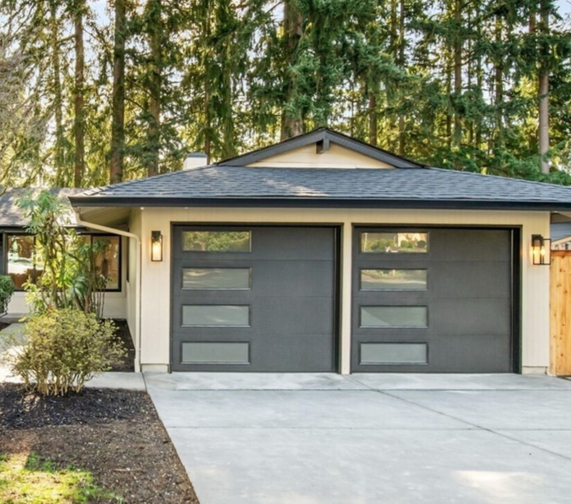 Gray contemporary garage door with window accents on a shingled home