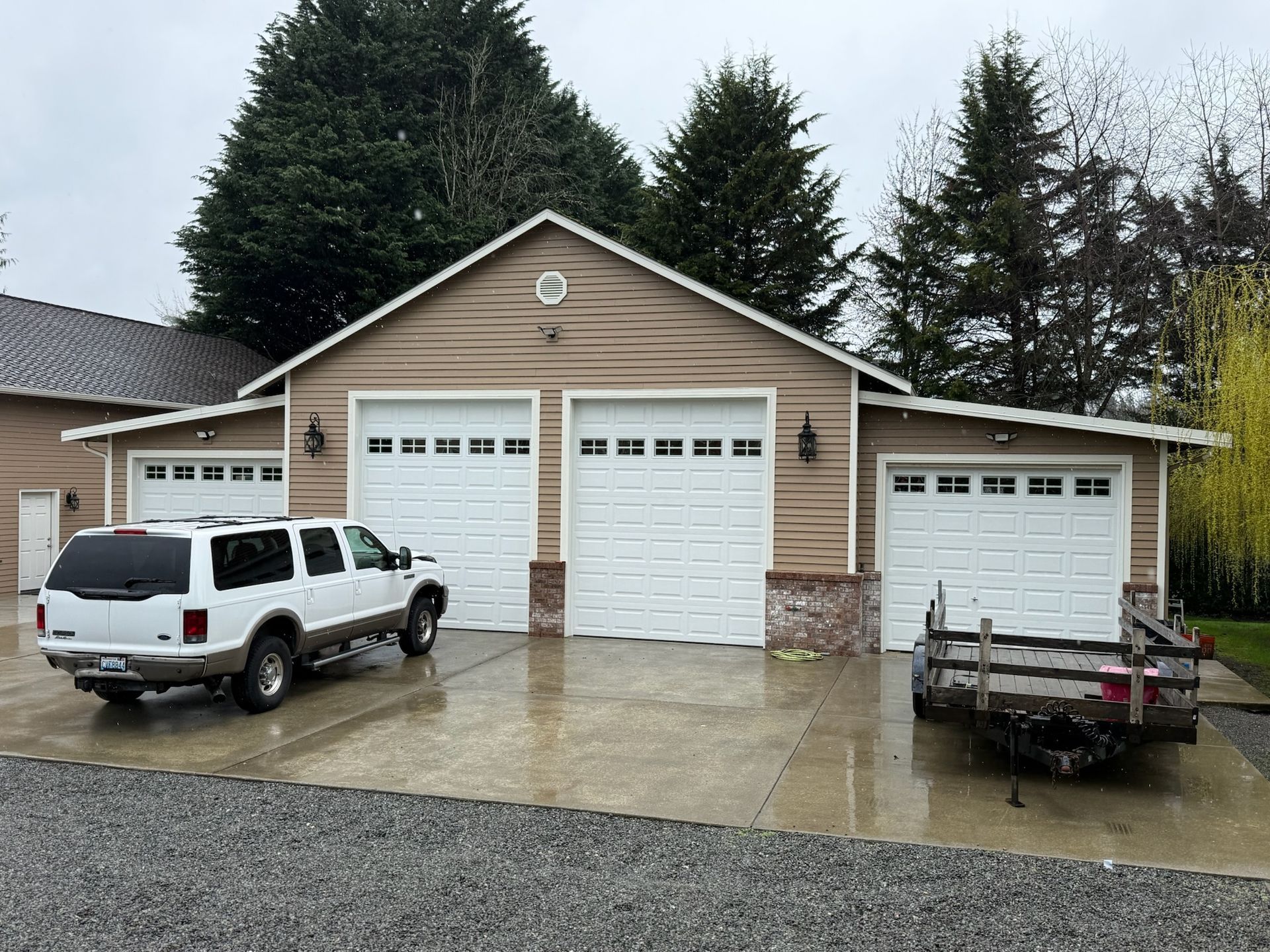 Three white traditional steel garage doors with vehicles parked outside