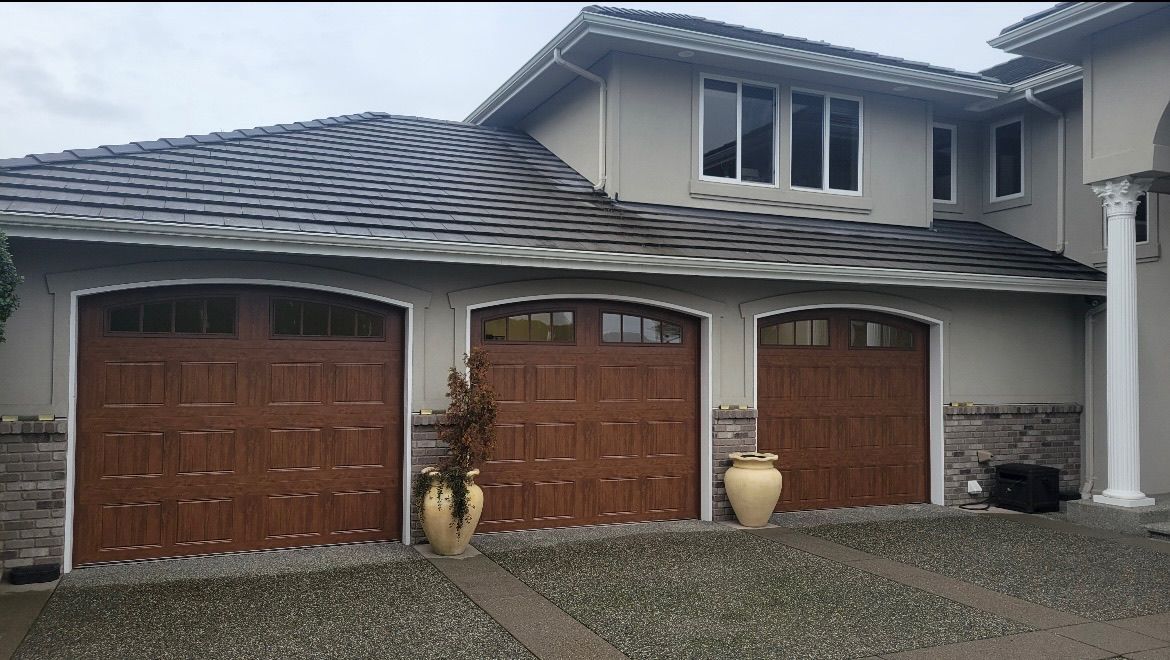 Arched traditional steel garage doors with wood-grain finish on a stucco home