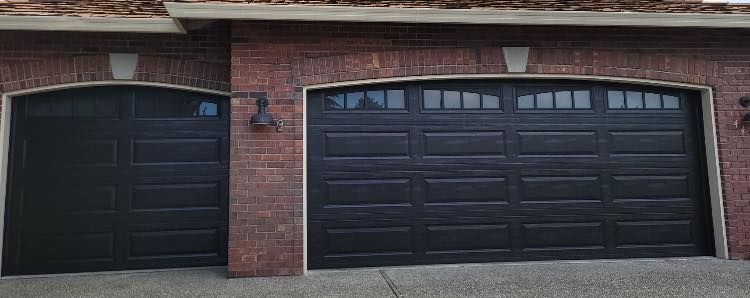 Black traditional steel garage door set into a red-brick facade