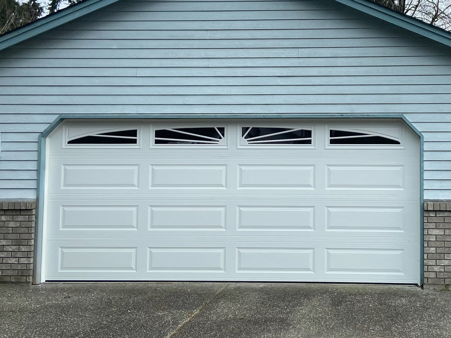 Sky-blue traditional steel garage door with sunburst window panes