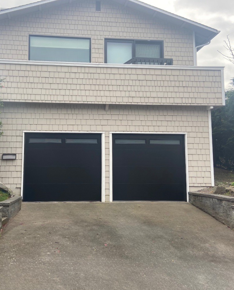 Black traditional steel garage door beside cedar shake siding