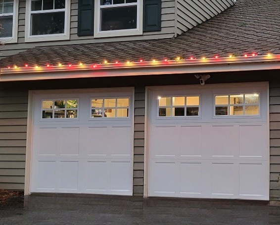 White traditional steel garage doors with square windows on a brown-shingled home