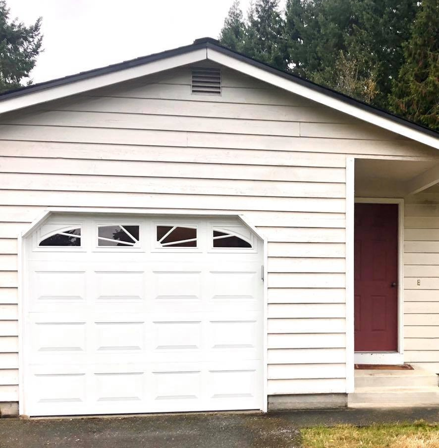 Home with a new white traditional steel garage door
