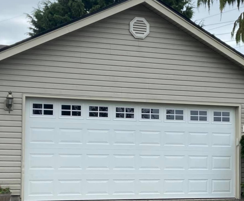 Home with a new white traditional steel garage door with windows