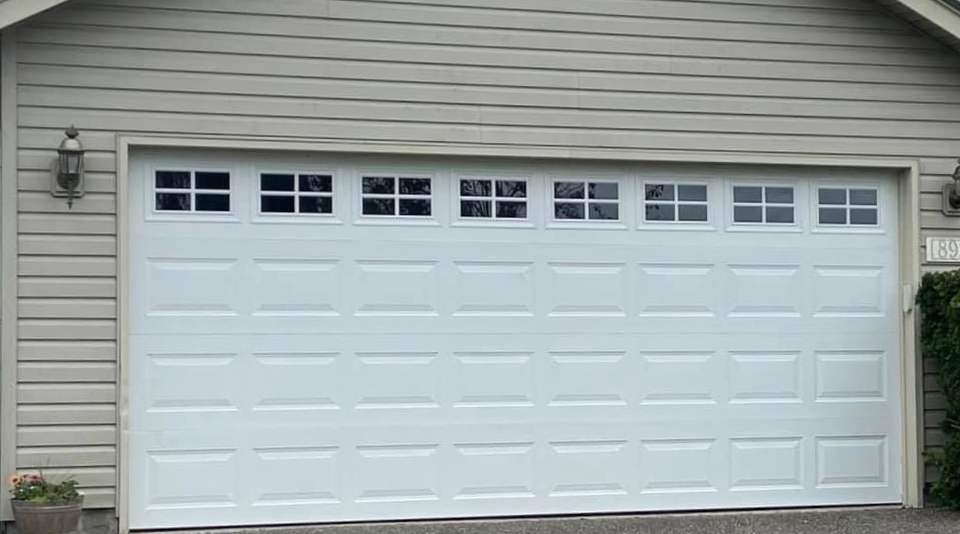 White traditional steel garage door with square windows on a tan home