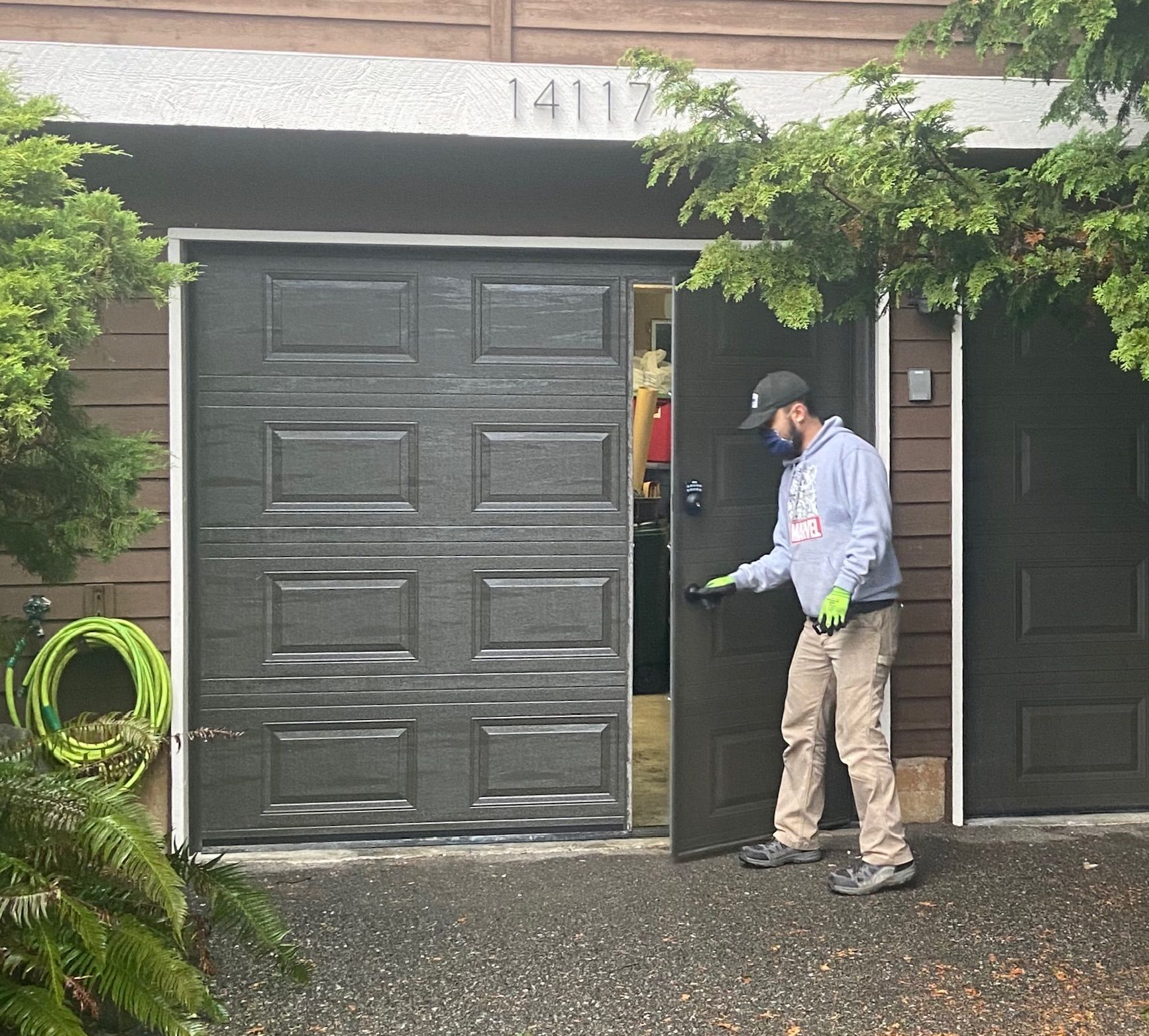 Technician servicing a dark green traditional steel garage door