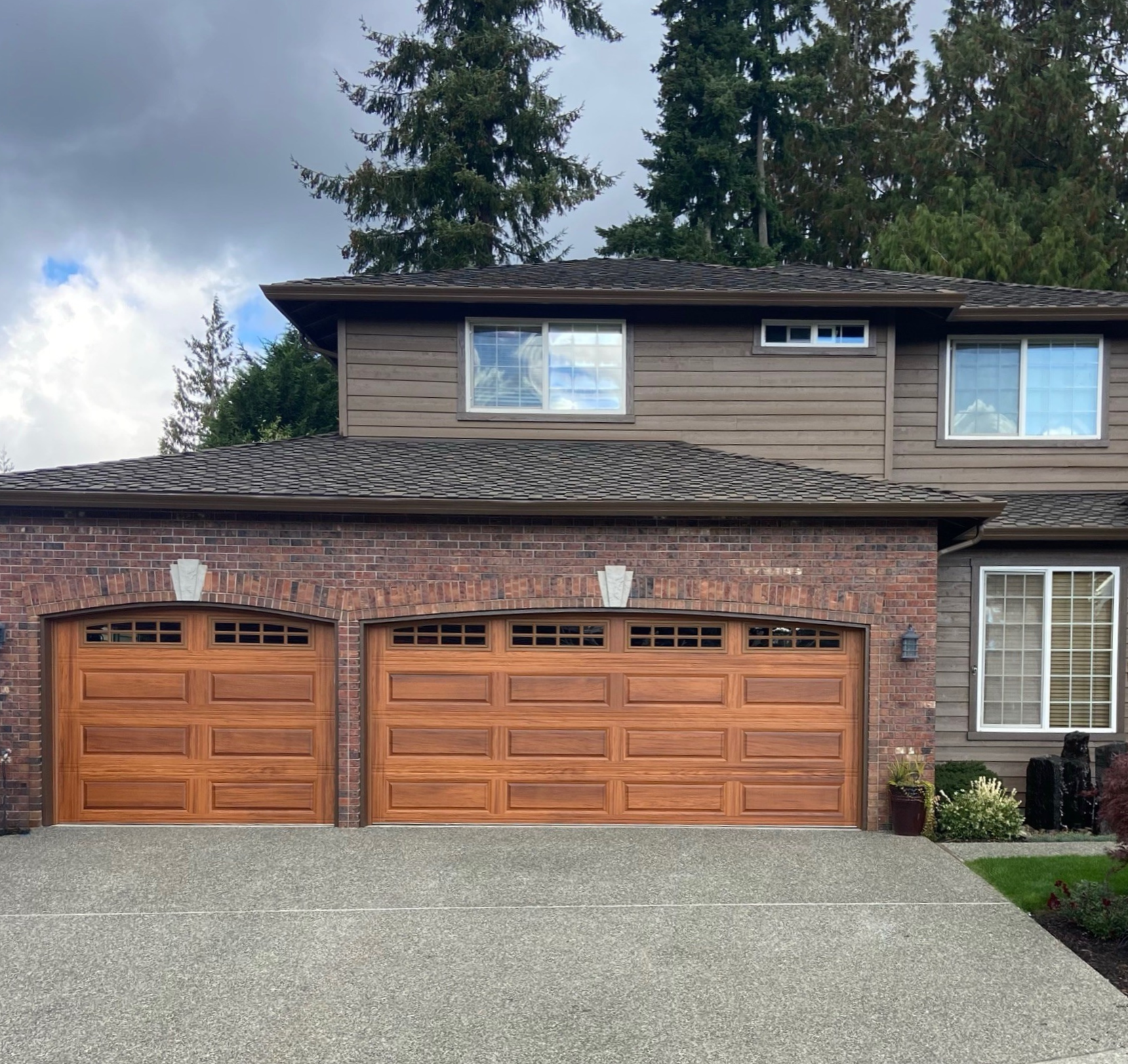 Cedar-stained arched traditional steel garage doors with diamond-pane windows