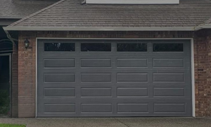 Dark bronze traditional steel garage door beside a brick entryway