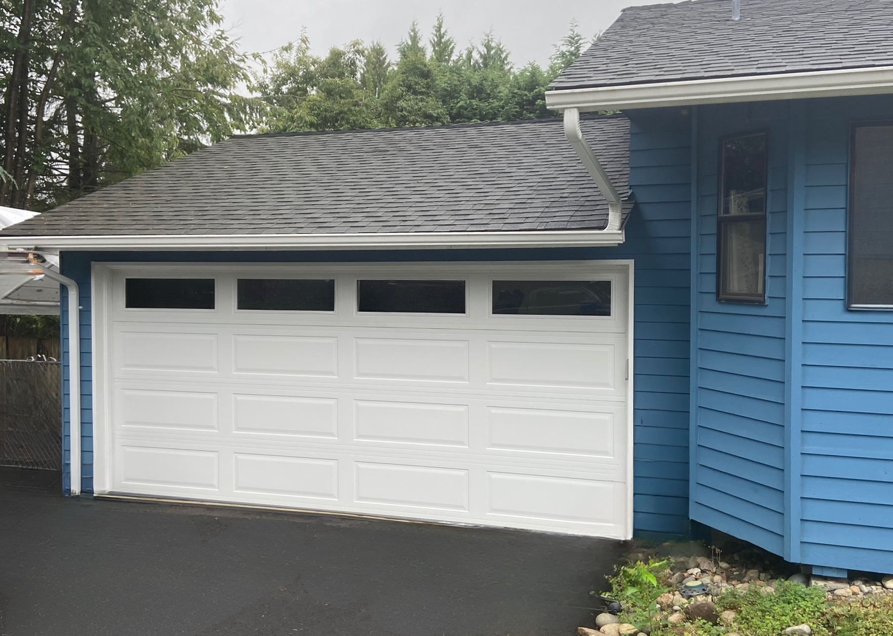 White traditional steel garage door on a blue-sided home