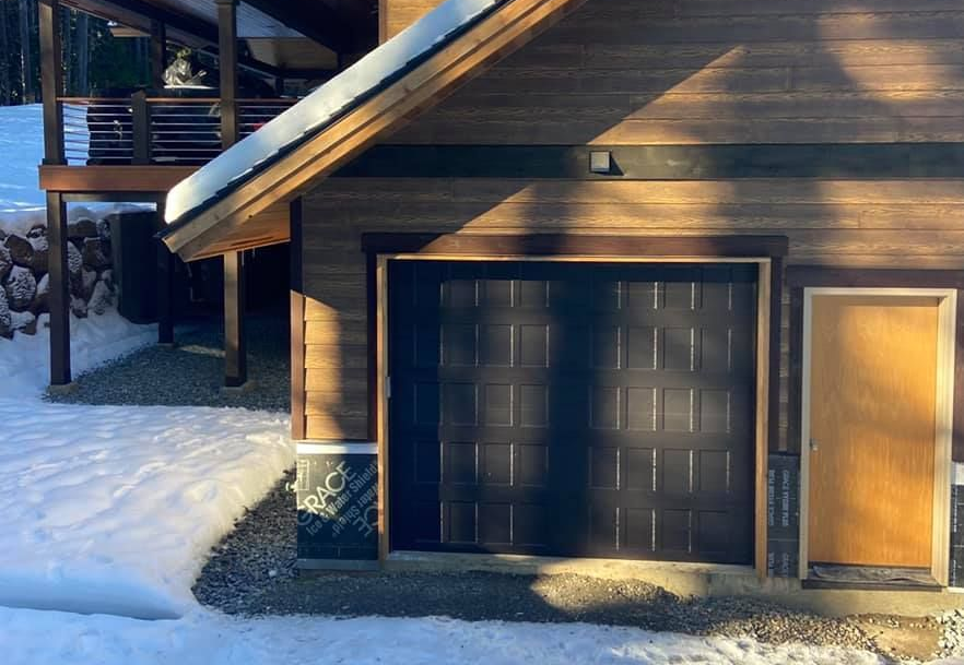 Close-up of a dark brown traditional steel garage door framed in snow