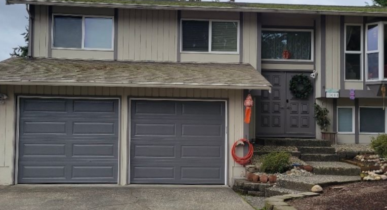 Gray traditional steel garage doors on a two-story home with a walkway entry