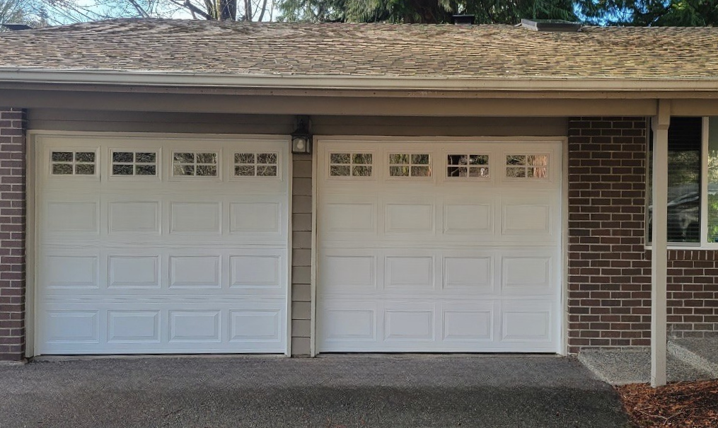White traditional steel garage doors with square windows on a brick ranch home
