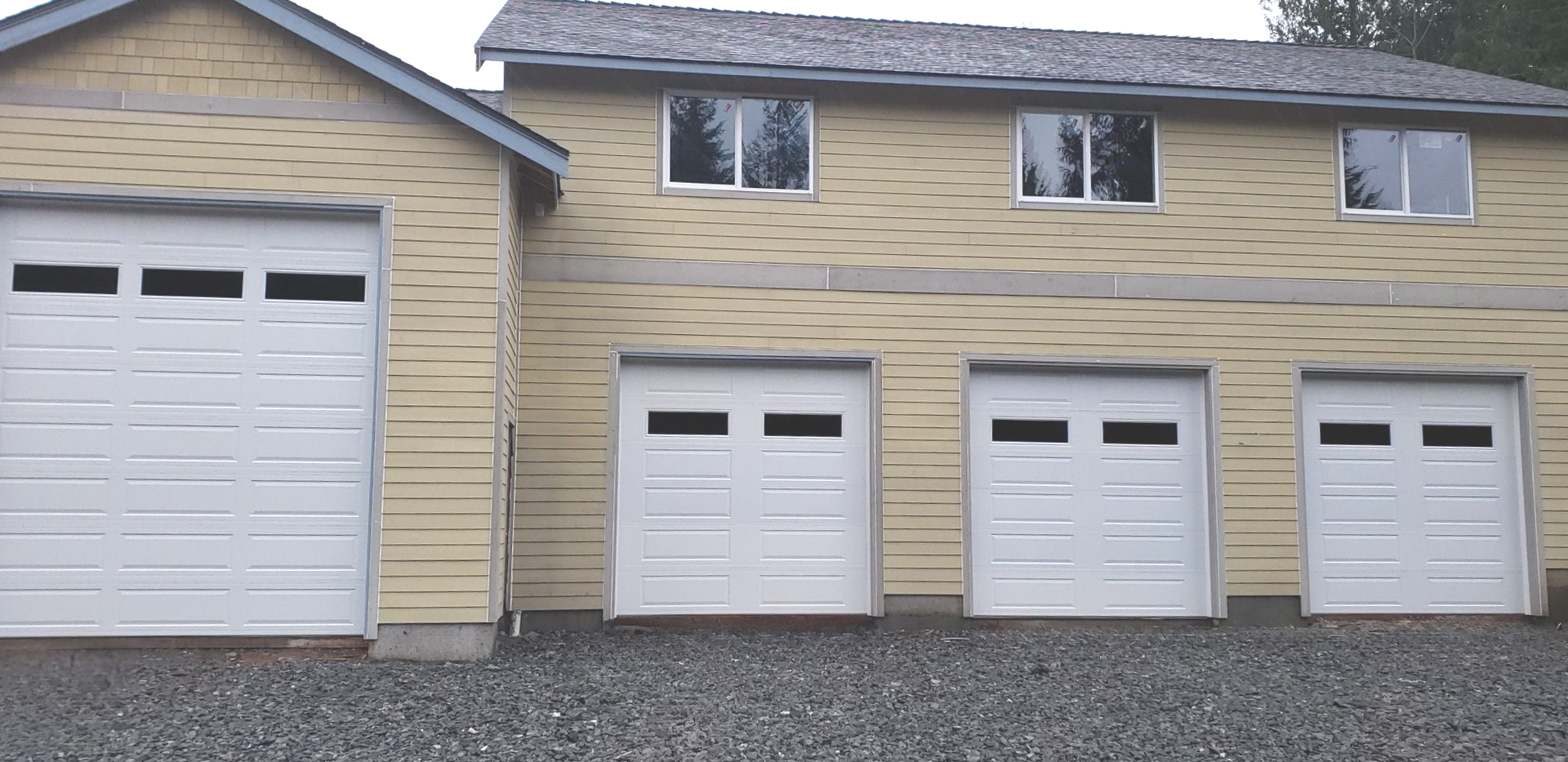 Three-car home with white traditional steel garage doors, including an additional RV garage door