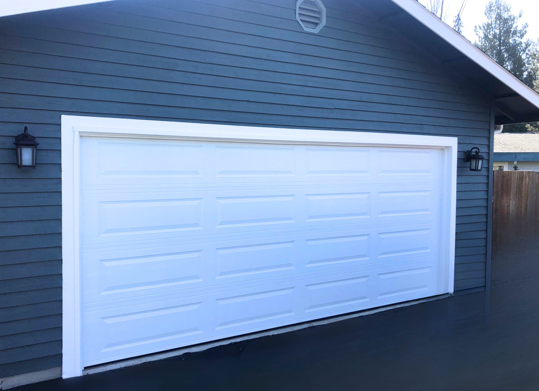 White traditional steel garage door on a navy-blue home