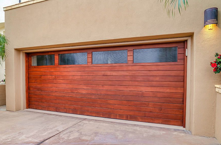 Reddish wood-tone contemporary garage door with horizontal slat paneling and a row of tinted glass windows