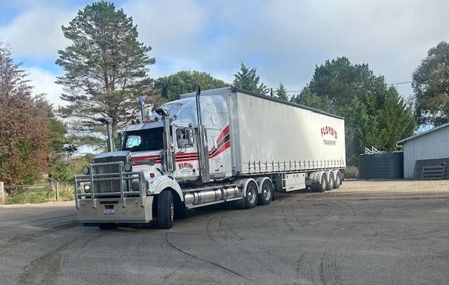 a row of semi trucks are driving down a road.