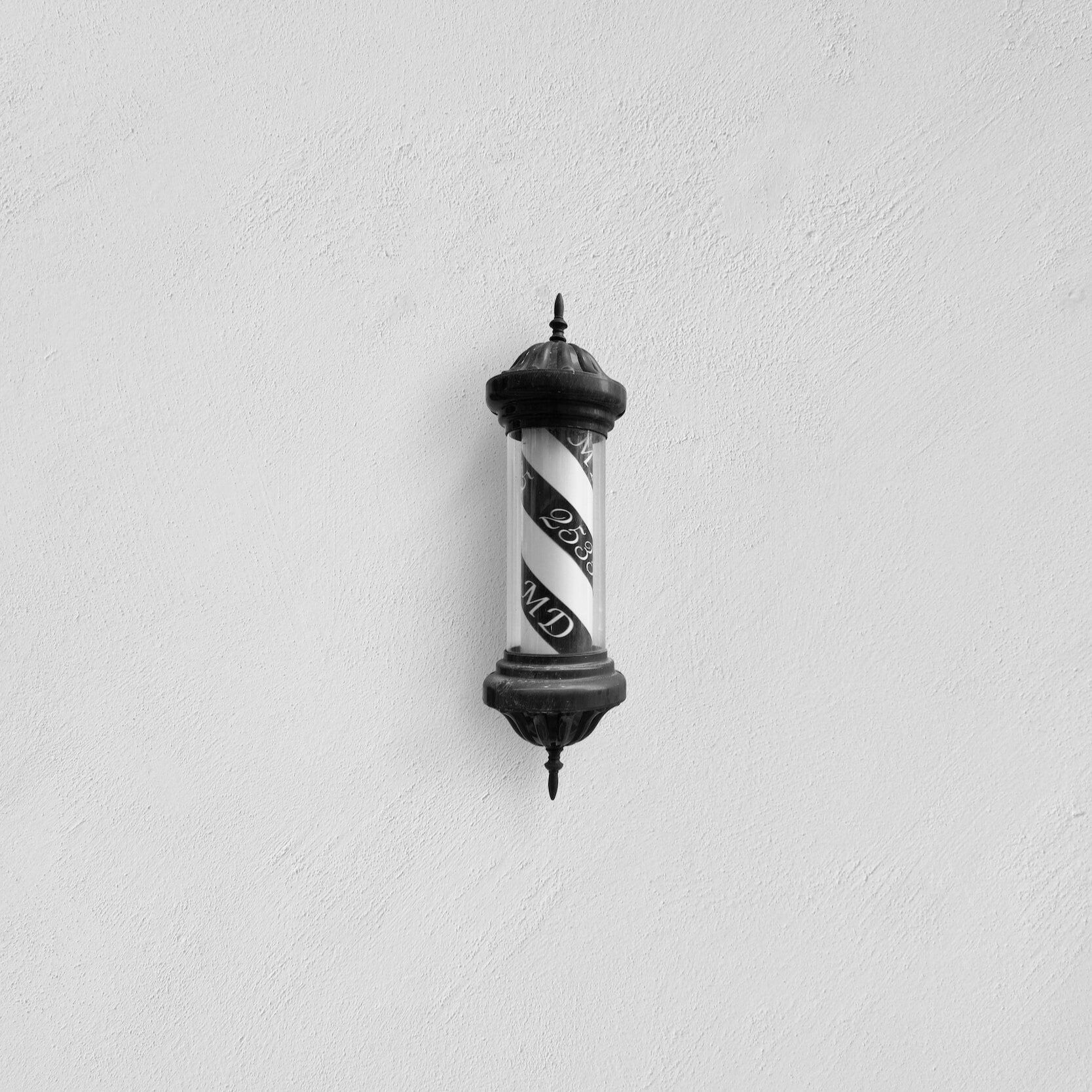 Scissors hanging on a wooden wall, some with black or dark green handles.
