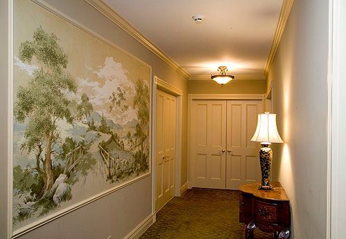 A hallway with a painting on the wall and a lamp