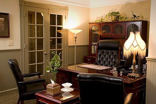 An office with a desk and chairs and a lamp