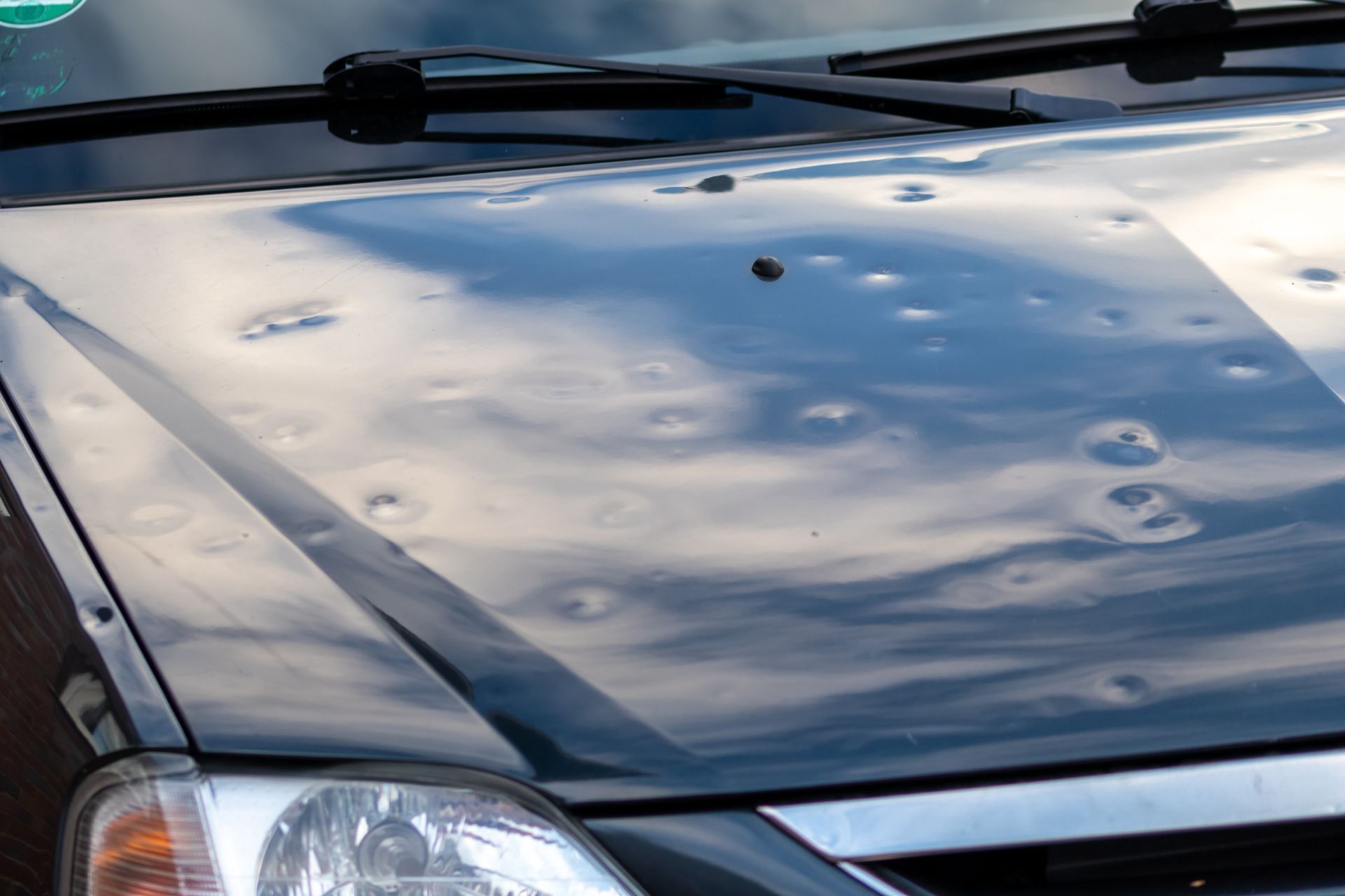 a black car with hail damage on the hood