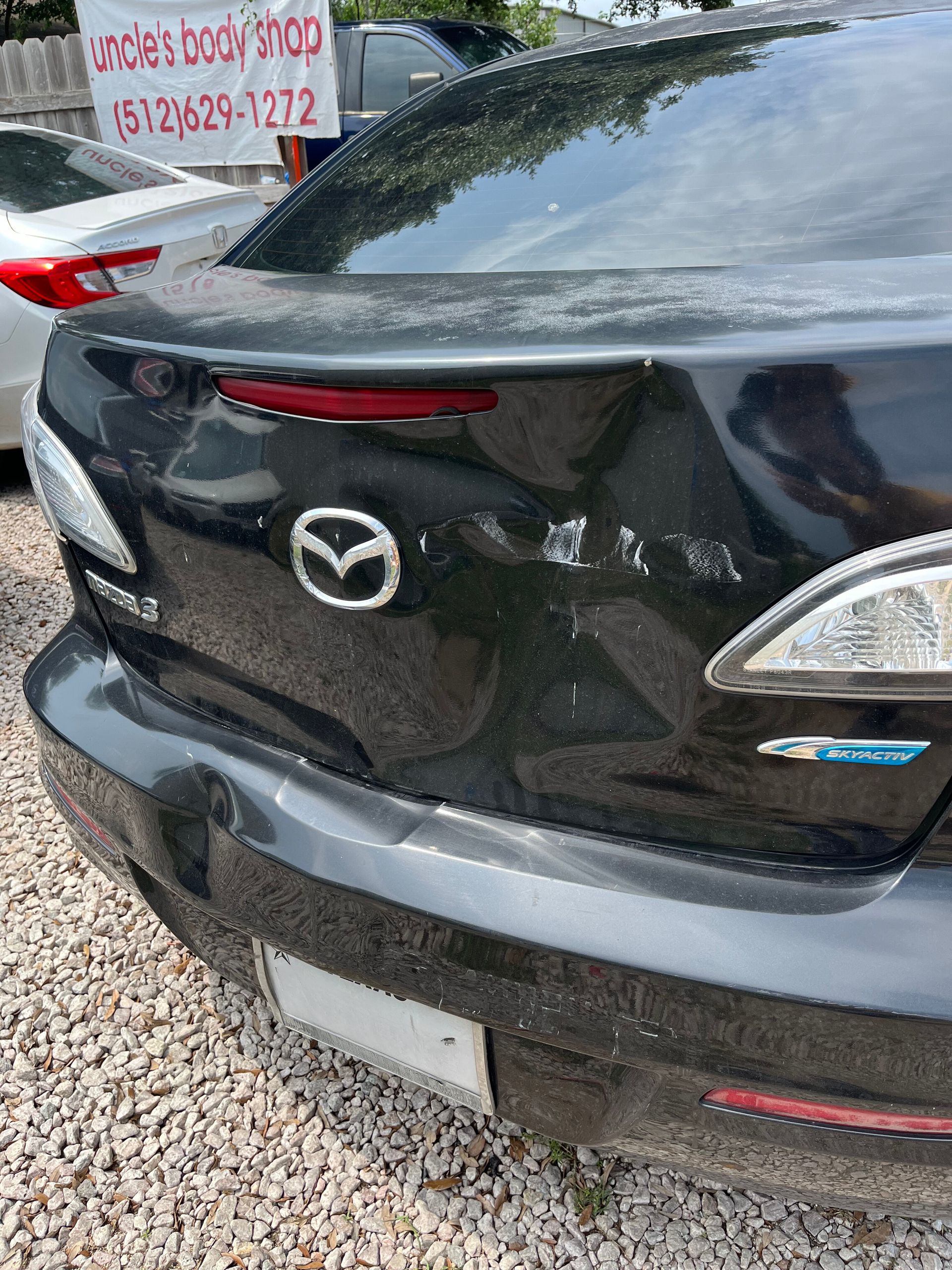 A black mazda 6 is parked in a gravel lot.