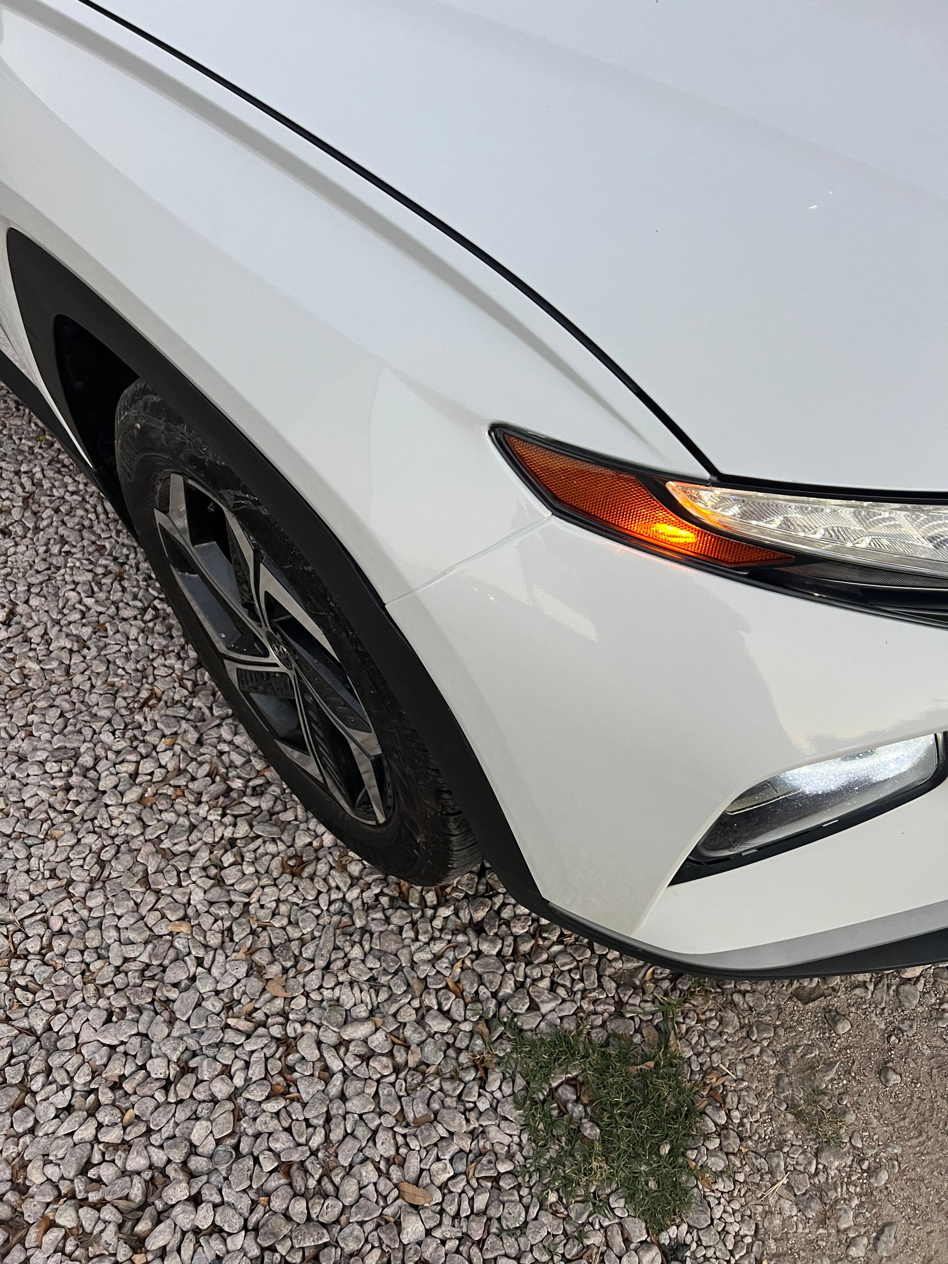 A close up of a white car parked on gravel