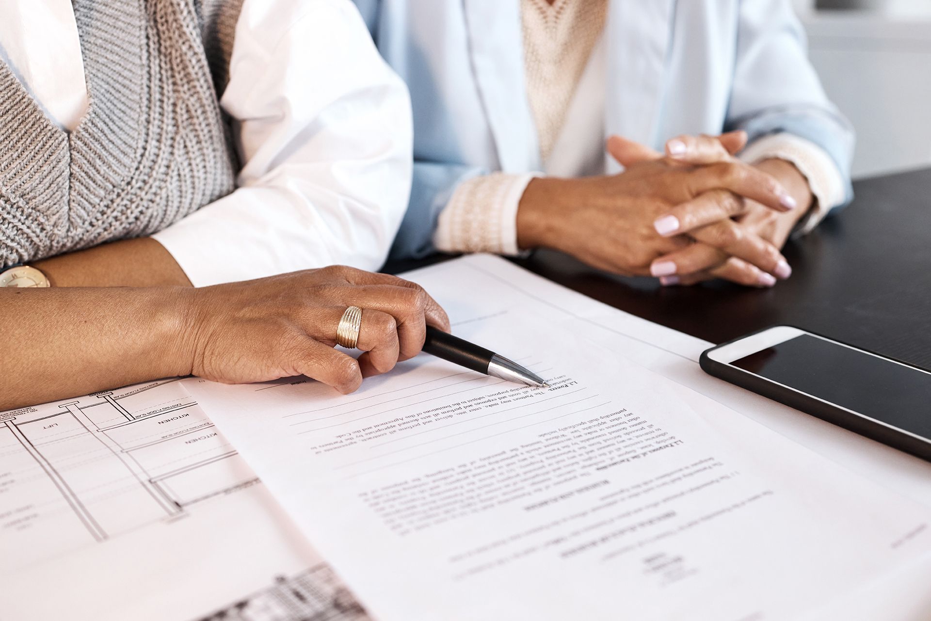 Two women are sitting at a table looking at a piece of paper.