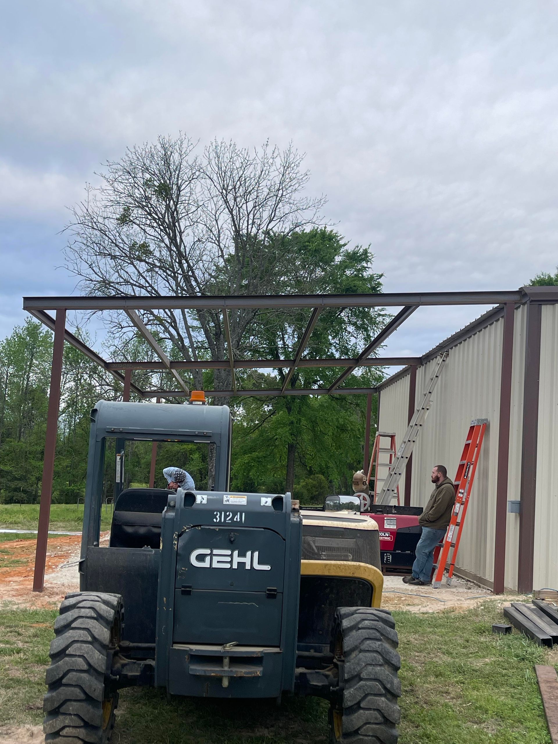 GEHL skid steer in a construction area beside a building frame and materials