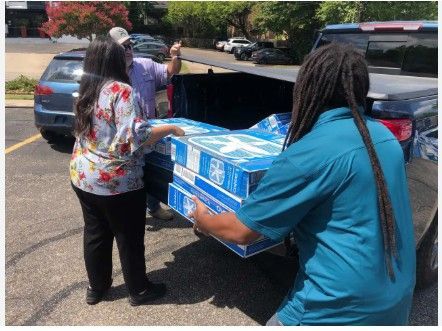 Two people unload boxes from the back of a pickup truck in a parking lot.
