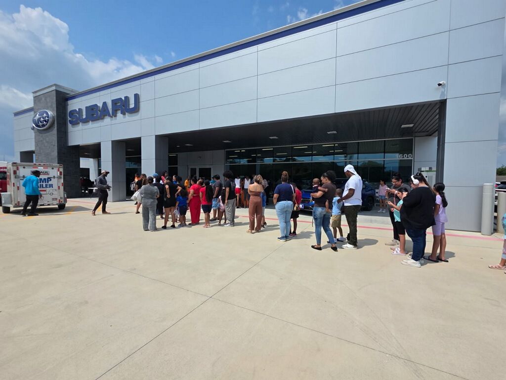 People lined up outside a Subaru dealership on a sunny day for the 2025 Mission Back 2 School Event