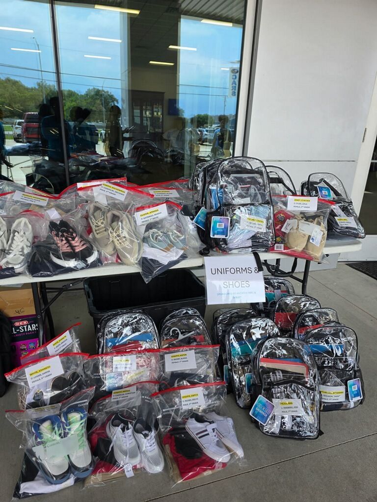 Table with plastic-wrapped backpacks and shoes displayed outside a store