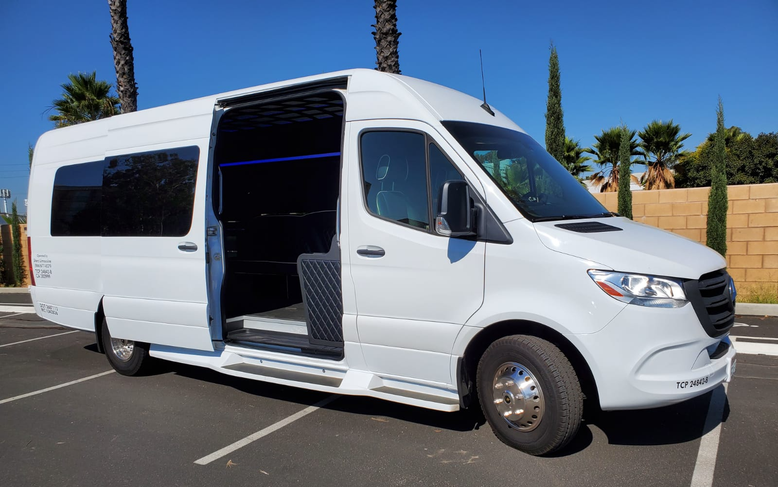 A white van is parked in a parking lot with its doors open.