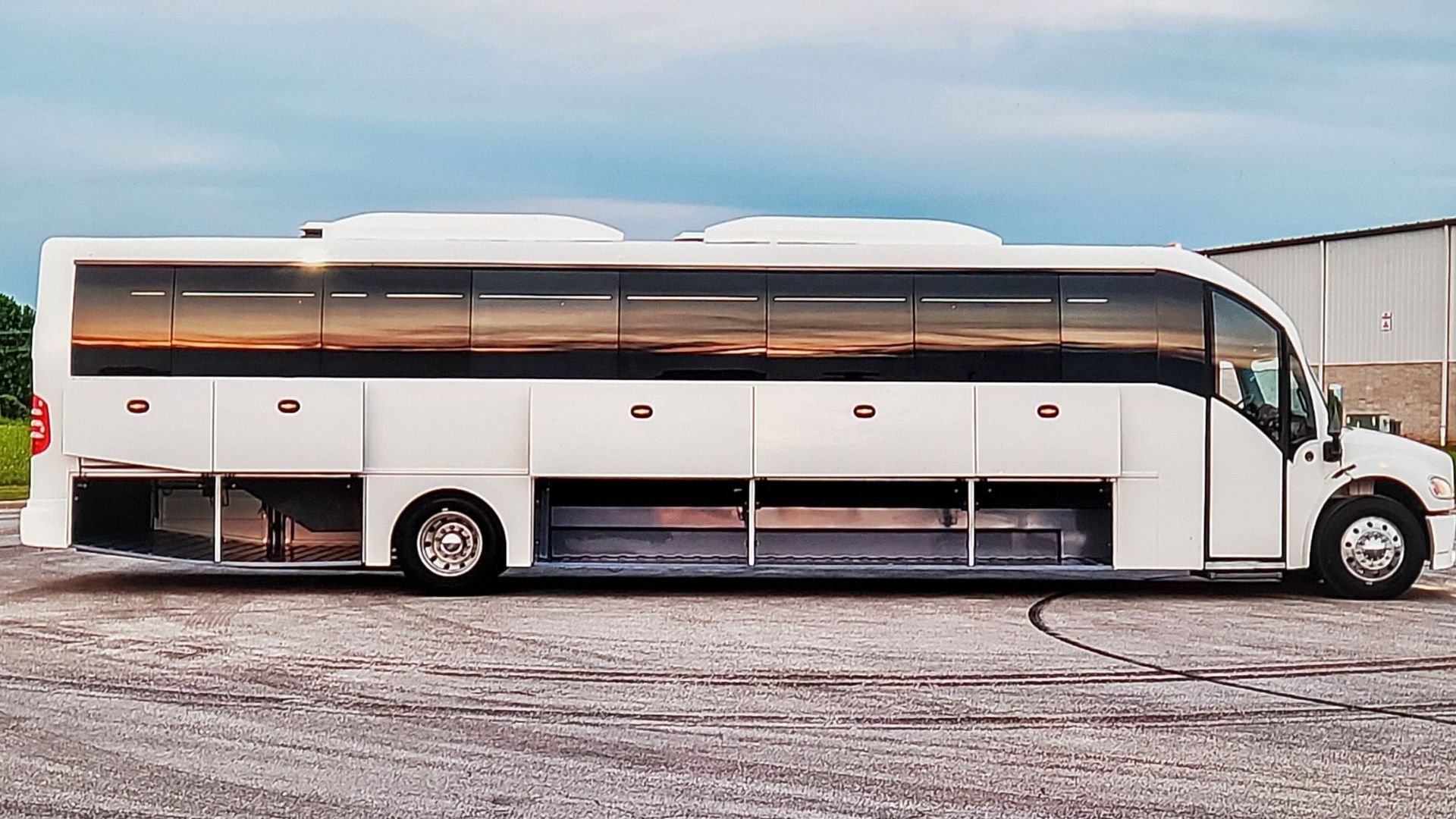 A large white bus is parked in a gravel lot.