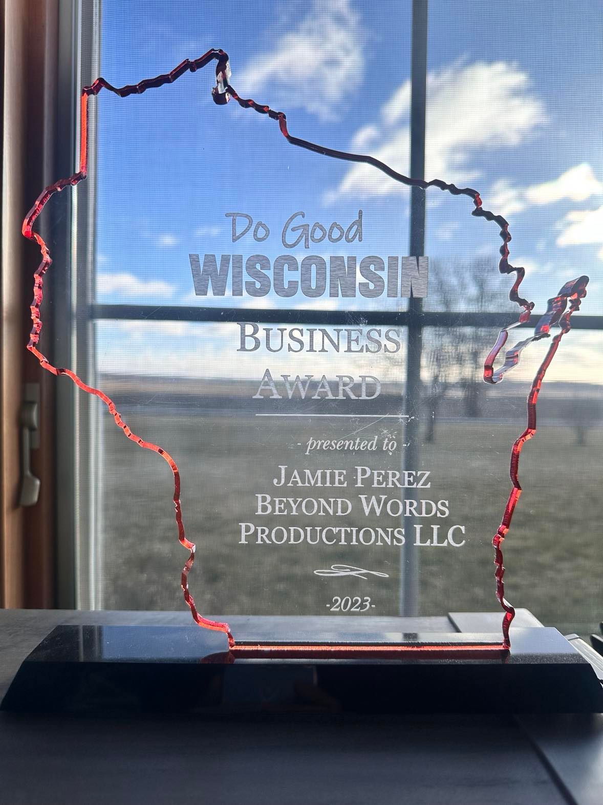 Wisconsin business award plaque shaped like the state, on a black base, in front of a window. Wisconsin business award plaque shaped like the state, on a black base, in front of a window.