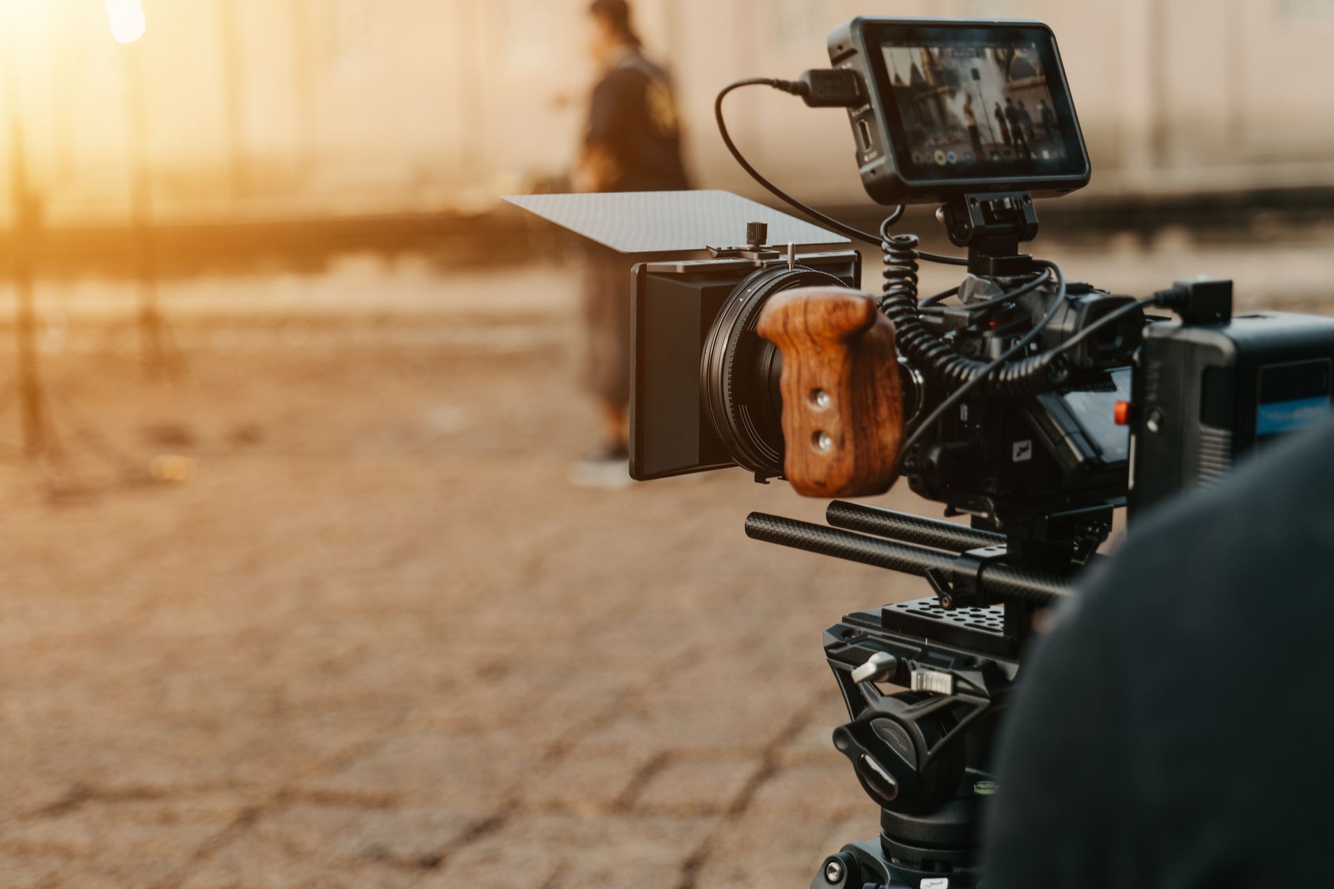 A person is holding a video camera on a tripod.