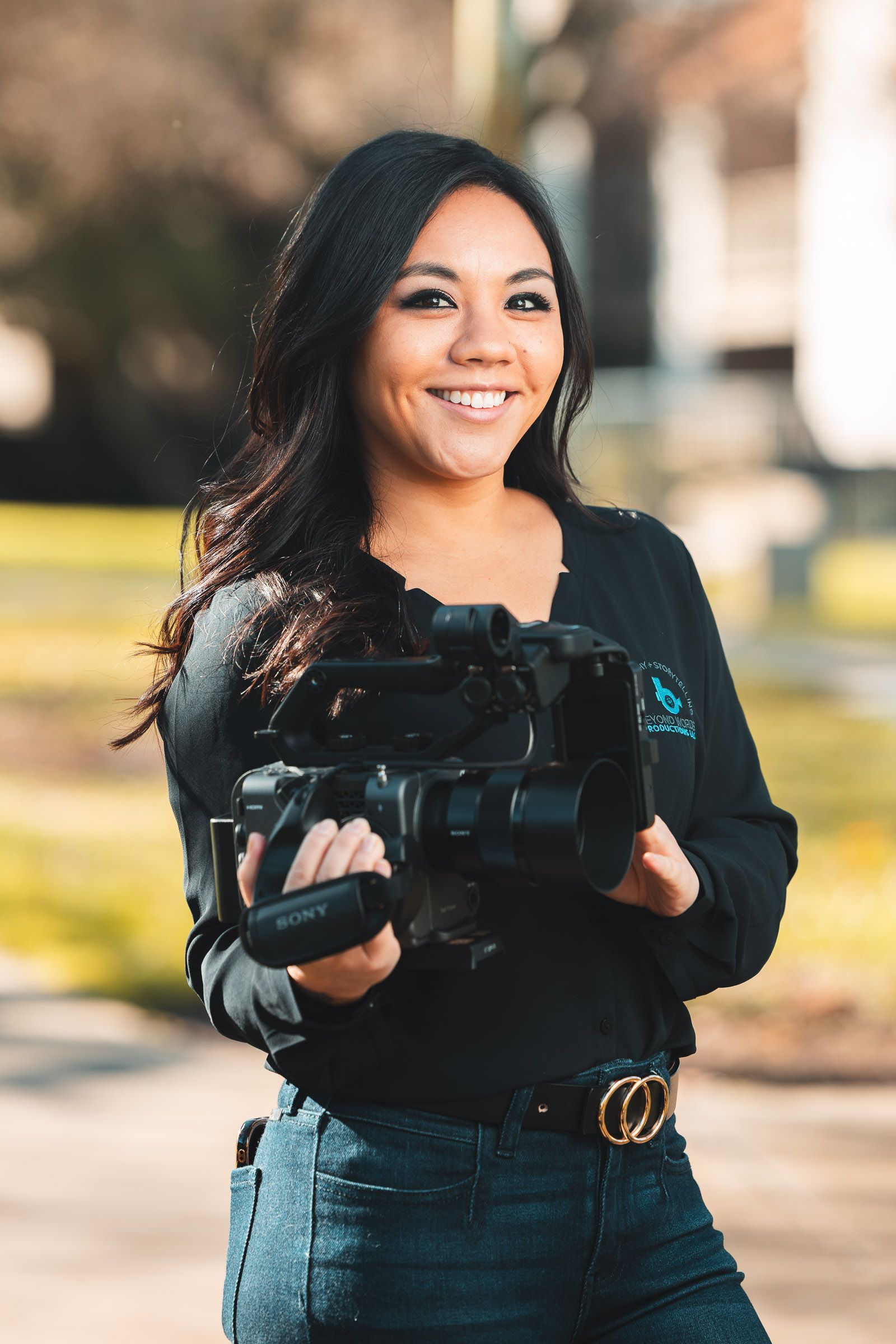 A woman is holding a camera in her hands and smiling.