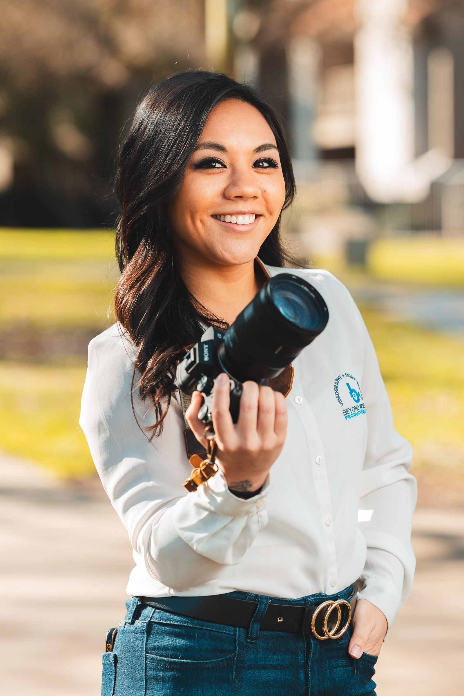 A woman is holding a camera in her hand and smiling.