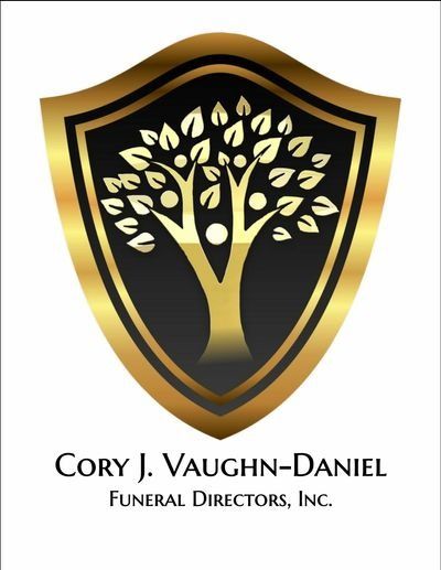 Gold-and-black shield logo with a stylized tree; text reads “Cory J. Vaughn-Daniel Funeral Directors, Inc.”