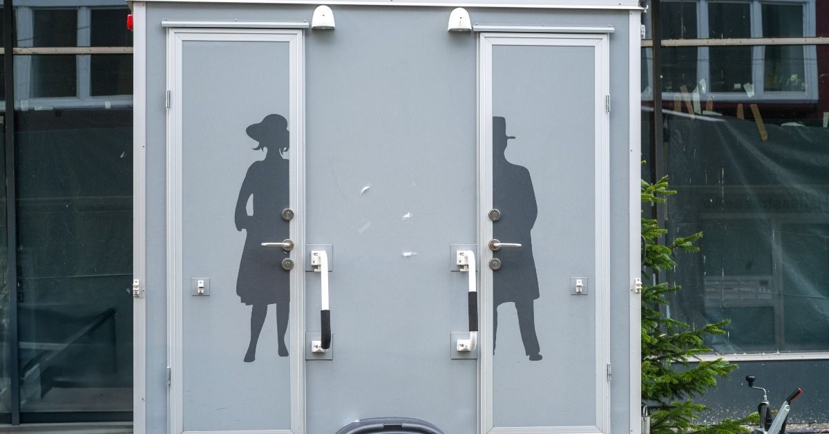 A mobile restroom trailer with luxury amenities. The exterior features two doors, each with a gender-specific logo.