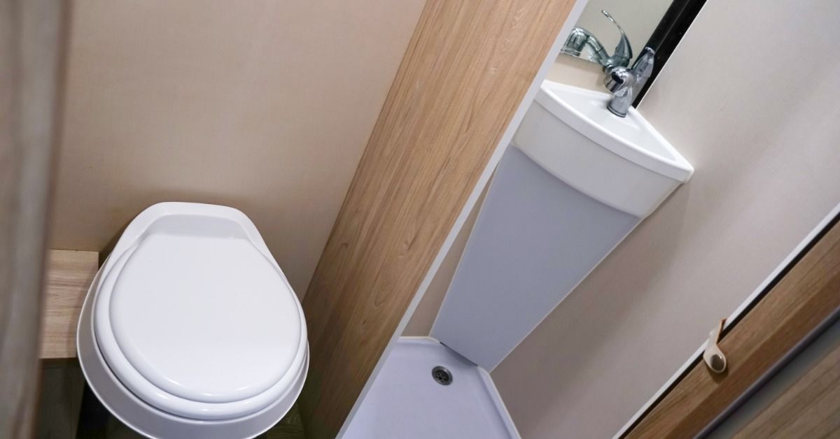 A close-up of the interior of a luxury restroom trailer with a white china toilet and a matching vanity area.